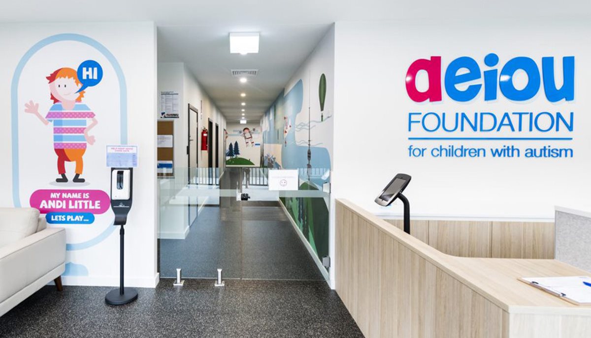 Entry to AEIOU Foundation childcare centre with logo on wall.